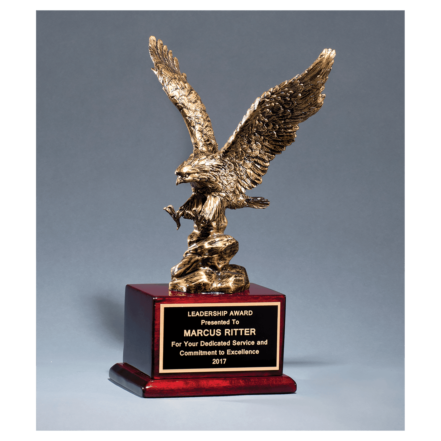Antique bronze finished eagle resin casting on a rosewood piano finish base with a black brass engraving plate, 15 inches tall