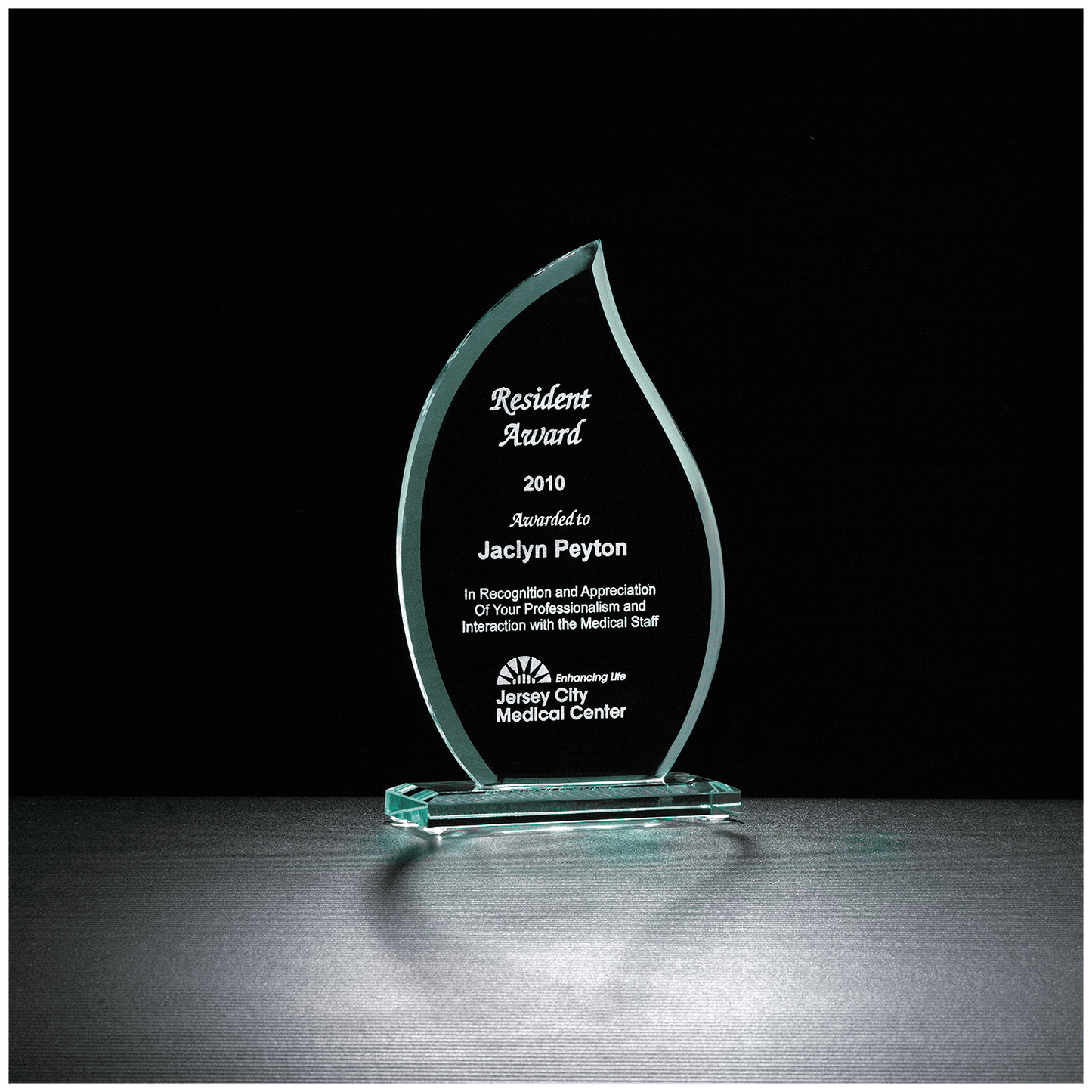 Jade green glass flame award on a matching glass base, engraved with a recognition message and company logo