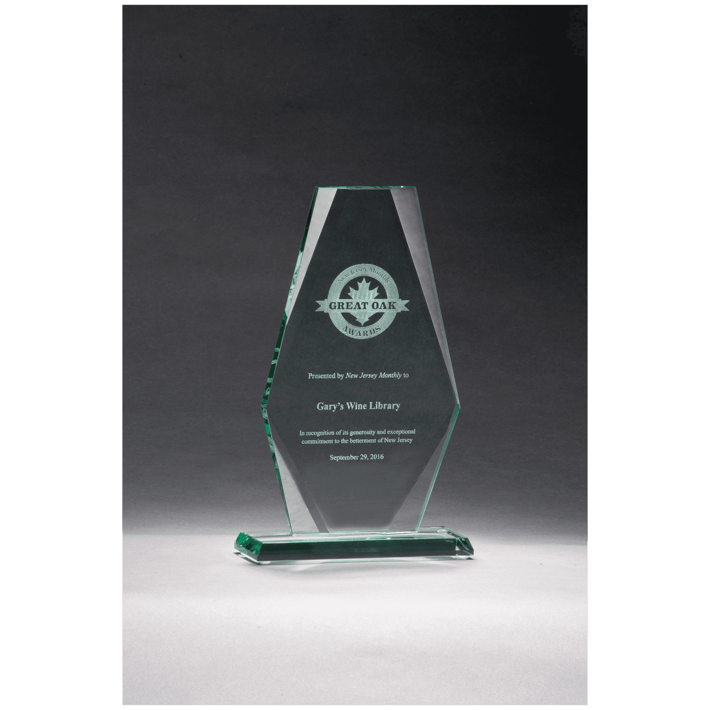 Glass award with engraved text on a dark background