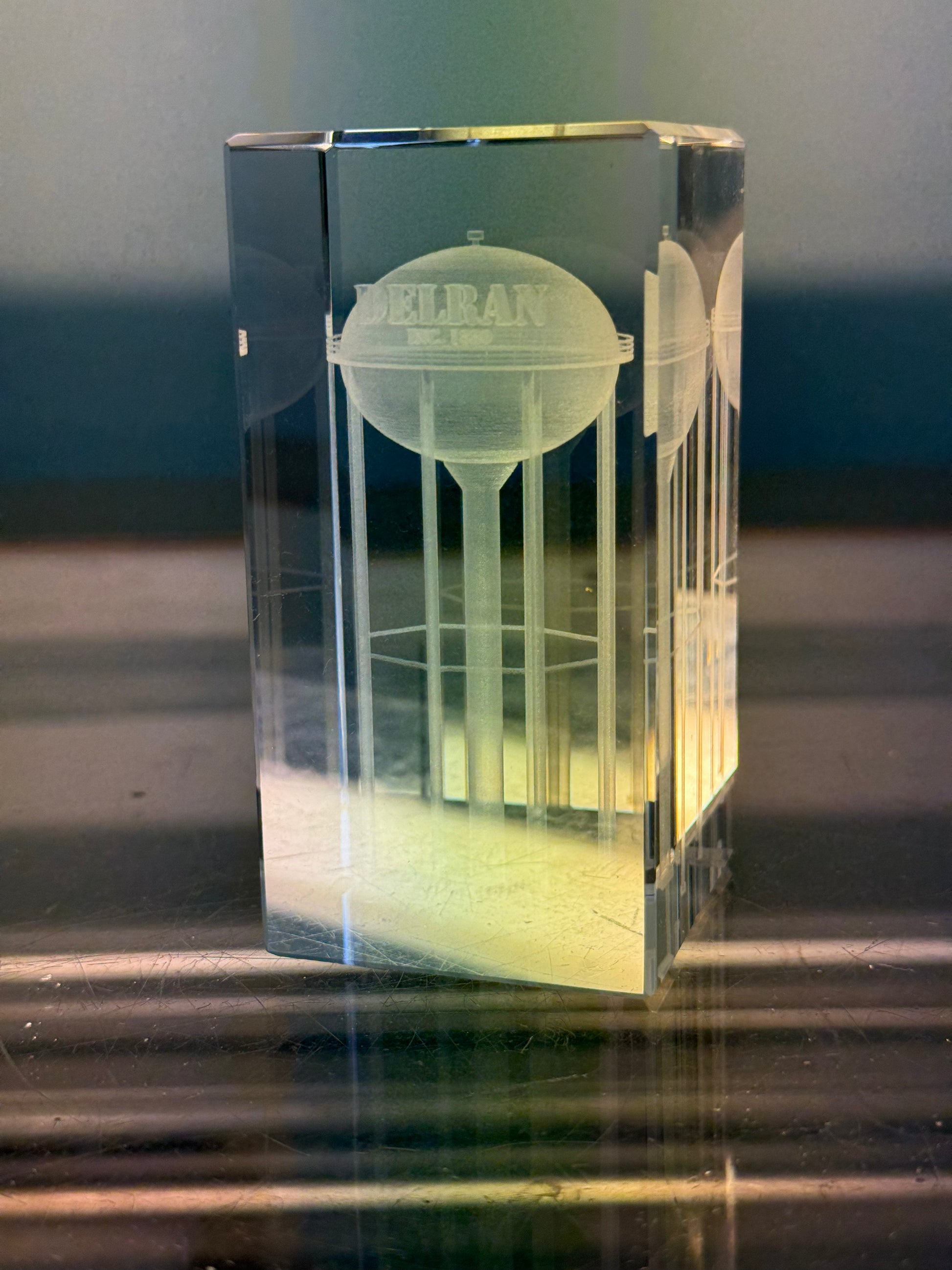 Clear crystal block with engraved water tower design on a reflective surface