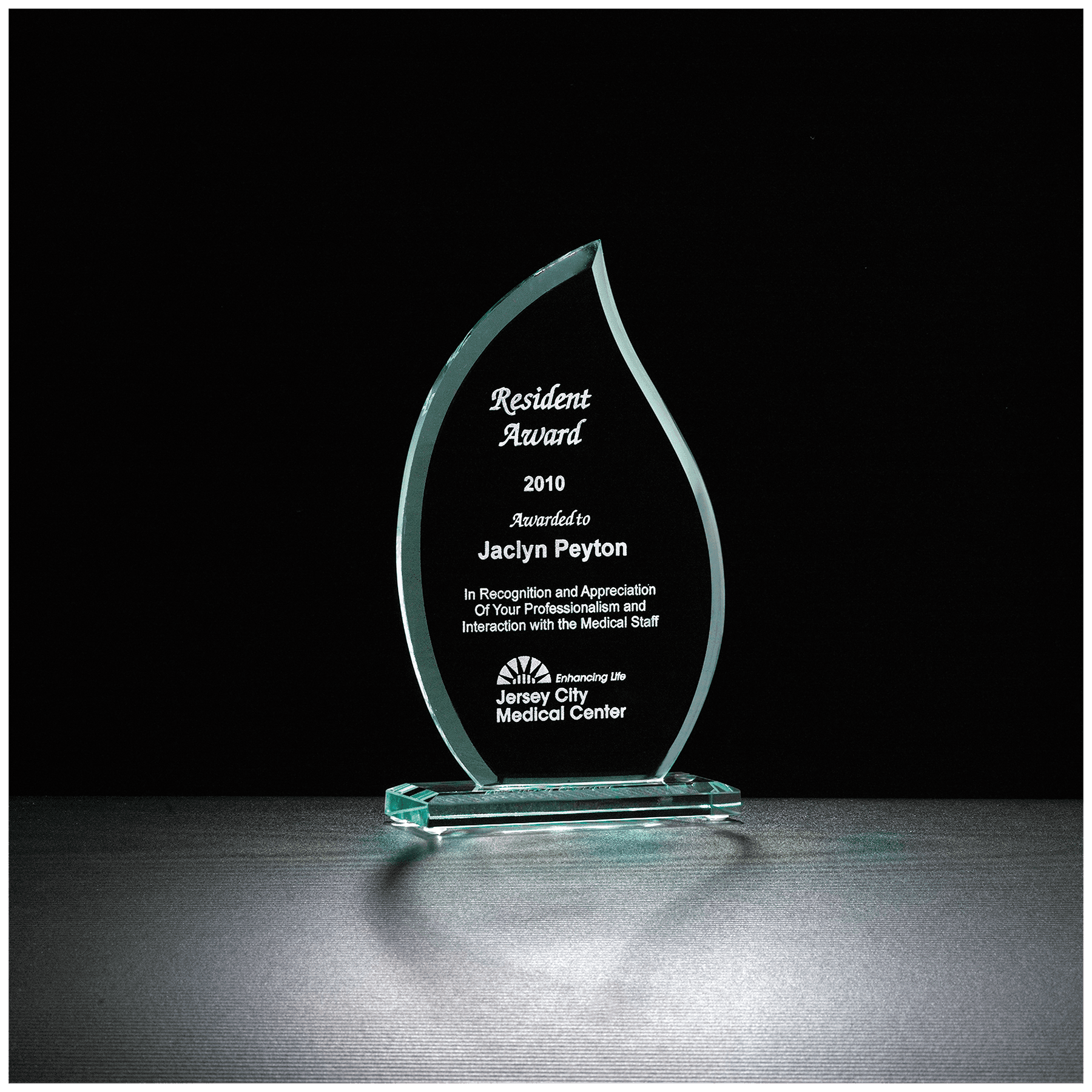 Jade green glass flame award on a matching glass base, engraved with a recognition message and company logo