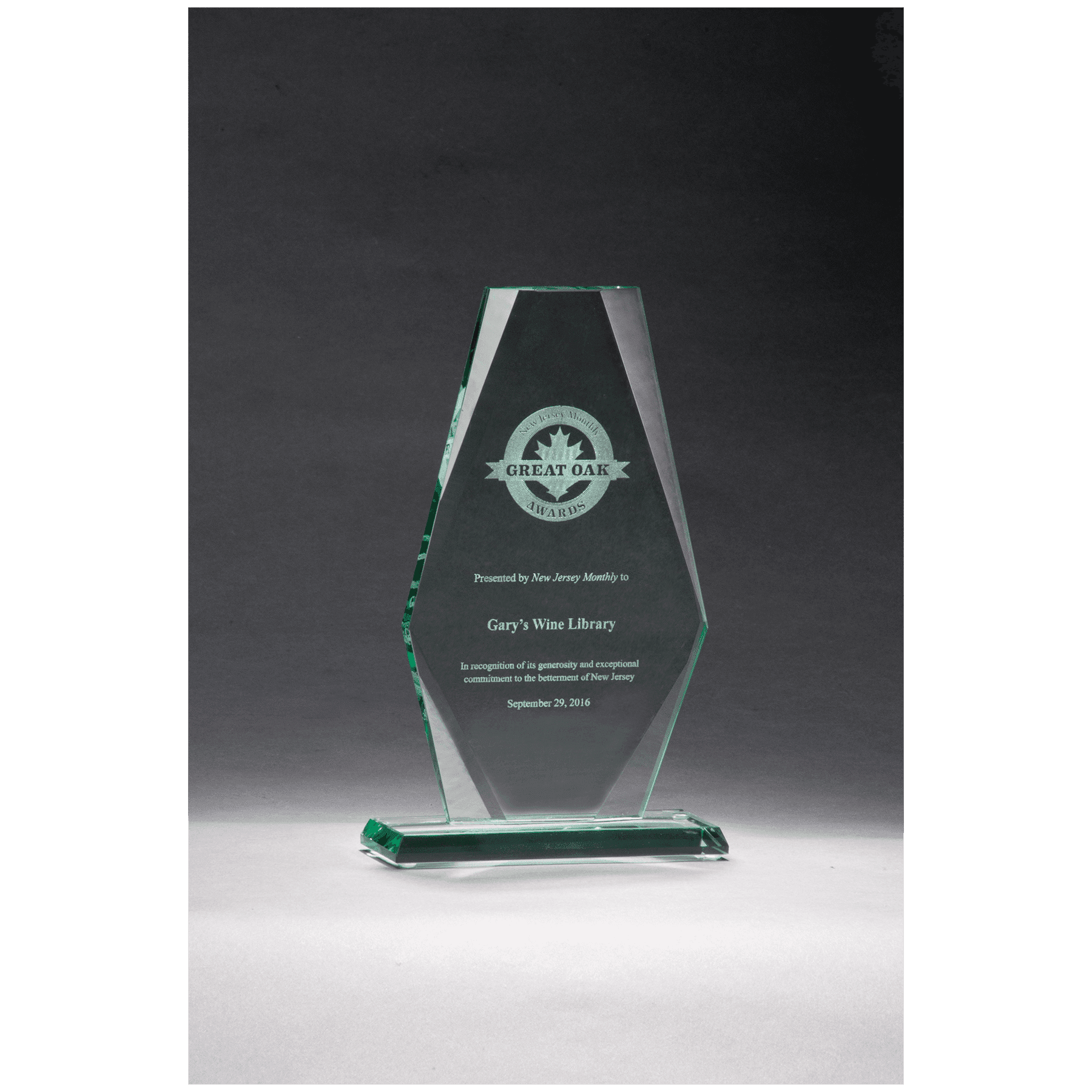 Glass award with engraved text on a dark background