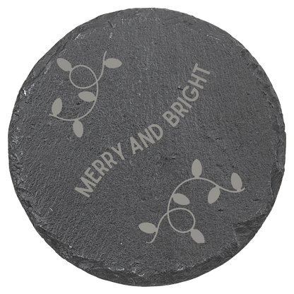 Round slate coaster with 'Merry and Bright' text and leaf designs on a clear background