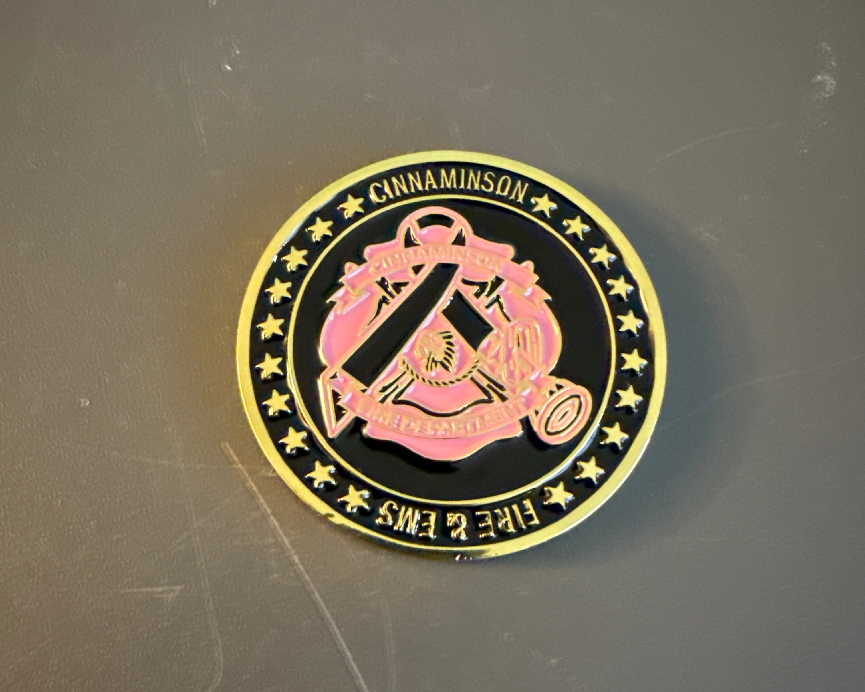 gold challenge coin in pink and black