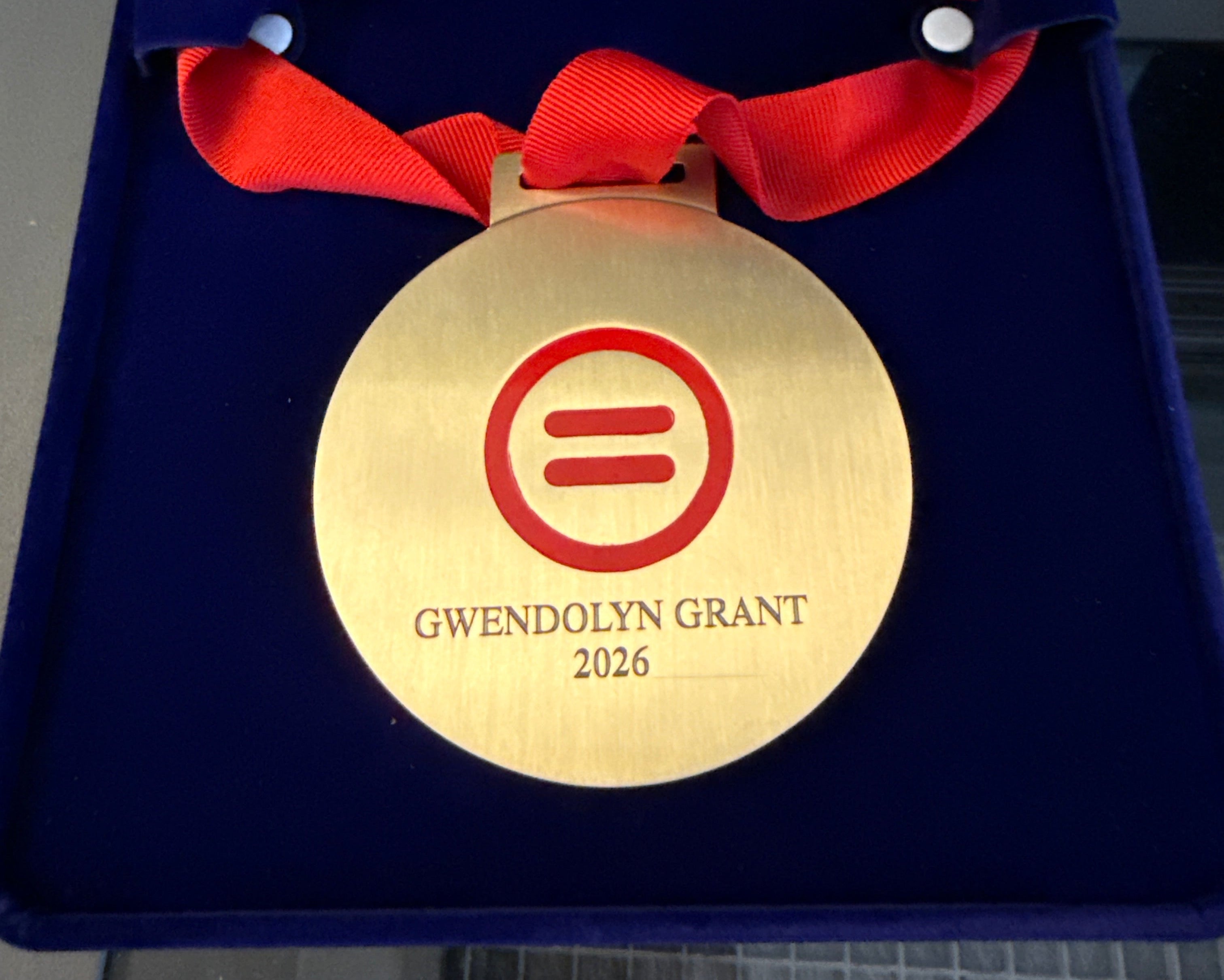 Gold medal with red ribbon and 'Gwenolyn Grant 2026' text on a blue box.
